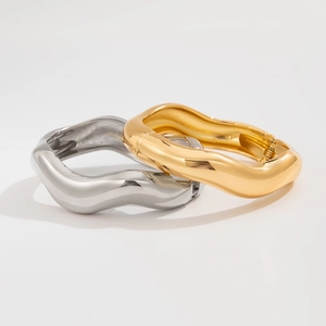 Detail of wave-shaped polished gold and silver metallic bangles with mirror finish