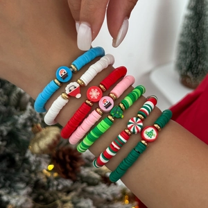 Détail de bracelets de Noël en argile polymère avec pendentifs festifs portés au poignet