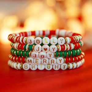 Close-up of five colorful Christmas clay bead bracelets with holiday words and gold accents