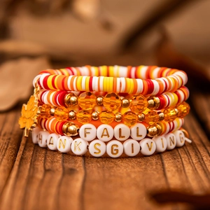 Detail of layered Thanksgiving bracelets with maple leaf charm and festive letter beads