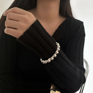 Detailed view of polished oval beads bracelet with metallic luster on model's wrist