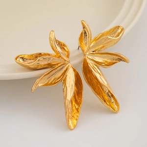 Detailopname van grote gouden blad oorbellen met een realistische metalen nerfstructuur afwerking