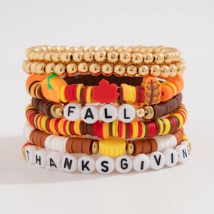 Detail of layered Thanksgiving bracelets with orange beads and FALL letter charms