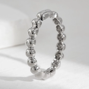 Close-up of polished silver beaded ring with mirror finish on white stone display