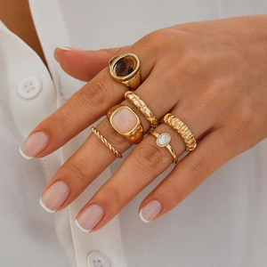 Detail eines 6-teiligen Goldring-Sets mit unregelmäßigen Edelsteinen und strukturierten Ringen