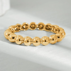Macro shot of polished gold bead ring with continuous spherical chain design on stone