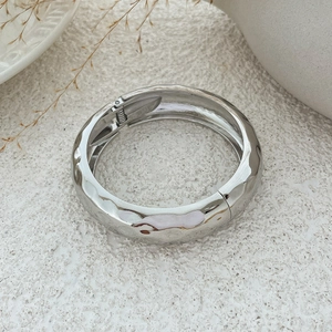 Detailopname van zilverkleurige gehamerde brede armband met scharnier en veersluiting