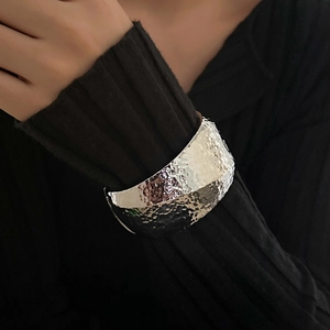 Detail of wide hammered texture open cuff bracelet in silver finish on black sleeve
