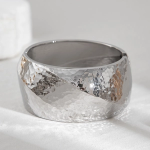 Detail of wide silver alloy bracelet showing unique hammered texture and metallic finish