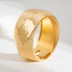 Macro shot of gold-plated wide cuff bracelet with hammered texture and hinge detail