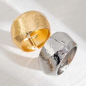 Macro detail of hammered gold and silver wide hinge bangles with textured metal finish