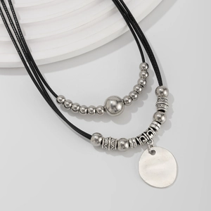 Macro detail of bohemian double-layer necklace with vintage silver charms on black cord