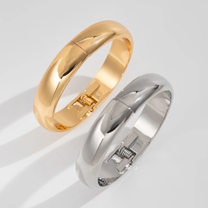 Detail of high-polished gold and silver spring cuff bracelets with shiny metallic finish