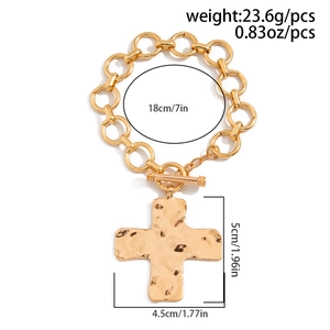 Detailoverzicht van gouden schakelarmband met gehamerde kruishanger en toggle sluiting