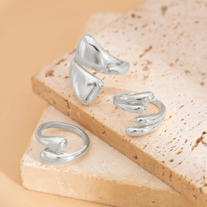 Close-up of three silver irregular organic rings on textured travertine stone background