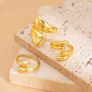Minimalist gold organic stackable rings set with fluid lava design on beige stone pedestal
