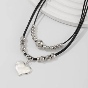 Detail of double-layer necklace with silver heart pendant and vintage beads on cord