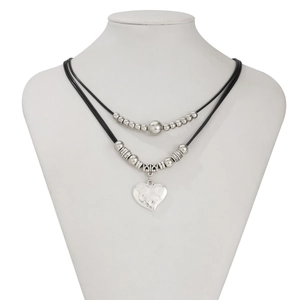 Detail of double-layer cord necklace featuring metallic beads and textured heart pendant