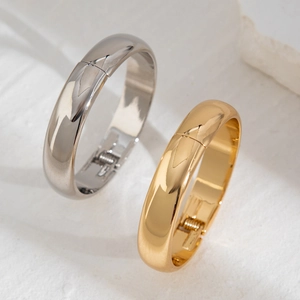 Polished gold and silver oval beaded spring bangles set on white marble surface