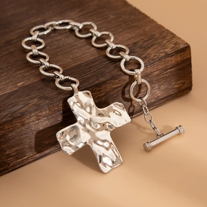 Detail van zilveren punk kruisketting met gehamerde textuur en vintage OT-knevelsluiting