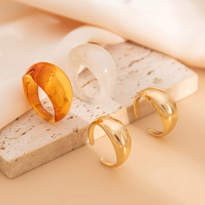 Detail van amberkleurige hars en gouden metalen ringen op natuursteen en zijde