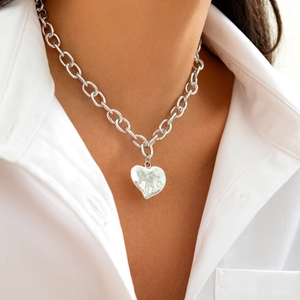 Dettaglio del ciondolo a cuore argento con texture martellata su catena a maglie