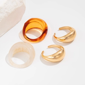 Gouden ringen set met amber en crème marmeren hars op een witte stenen achtergrond