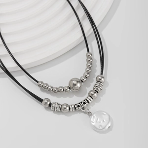 Detail of vintage layered necklace featuring silver beads and a shell pendant on a display