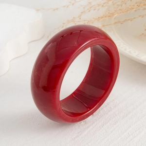 Close-up of a wide translucent red resin bracelet with a high-gloss polished finish