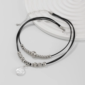 Detail of double-layer necklace featuring black cord, vintage beads and a baroque pearl pendant