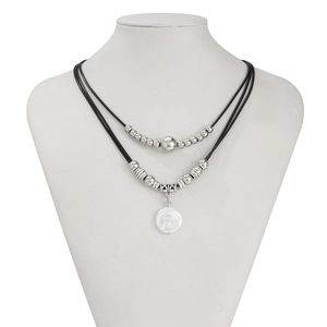 Detail of double-layer necklace featuring black cords, silver beads and white shell pendant