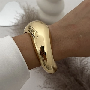Macro-opname van gepolijste gouden brede armband met gladde spiegelafwerking om de pols