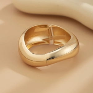 Detailopname van een gepolijste gouden chunky armband met een minimalistische metaallook