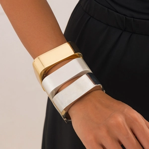 Macro shot of three square metal bracelets in gold, silver, and matte silver finishes