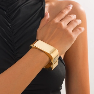 Close-up of golden geometric wide cuff bracelet featuring polished and brushed metal finish
