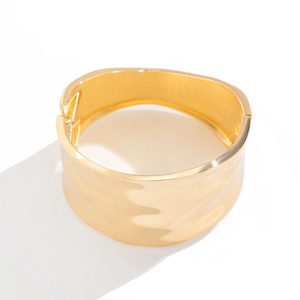 Detailed view of the wide golden hinge bracelet featuring irregular wavy hammer textures