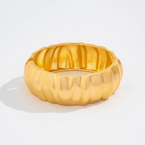 Detail of wide matte gold bracelet featuring vertical wavy texture and polished inner surface