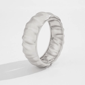 Detail of silver brushed metal cuff bracelet showing spring closure and rippled texture