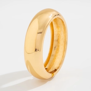 Detailed view of wide gold hinged cuff bracelet with polished surface and inner texture