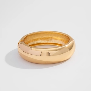 Detailed view of wide gold polished bangle with curved design and hinged closure