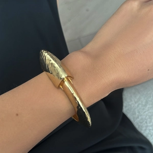 Macro detail of gold textured liquid metal cuff bracelet with lava irregular finish