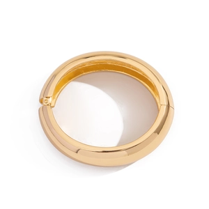 Macro detail of wide gold polished bangle showing the smooth finish and hinged closure