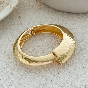 Macro view of gold hammered texture metal bracelet with a spring hinge closure