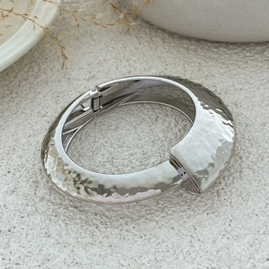 Detailed view of silver hammered texture metal bracelet with spring hinge closure