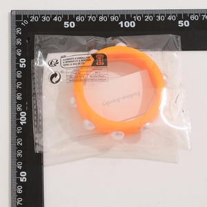 Vista detallada de brazalete ancho naranja de resina con incrustaciones de perlas blancas