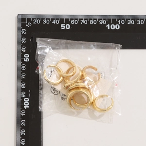 Gros plan de bagues gouttes dorées en emballage transparent avec règle pour les dimensions