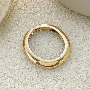 Polished gold wide cuff bracelet with geometric metal texture on stone background