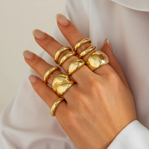 Close-up of stacked gold-finish irregular rings with high-shine metallic texture