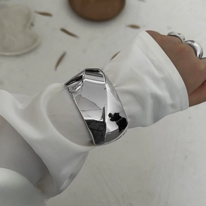 Minimalist wide silver metal cuff bracelet and rings set with polished mirror finish