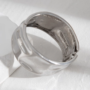 Detail of silver twisted metal cuff bracelet with hammered texture and spring hinge